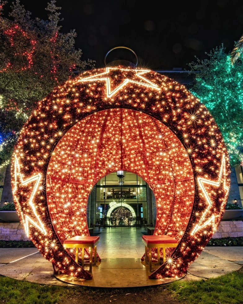 A massive red LED ornament decorated with glowing stars and two benches inside.