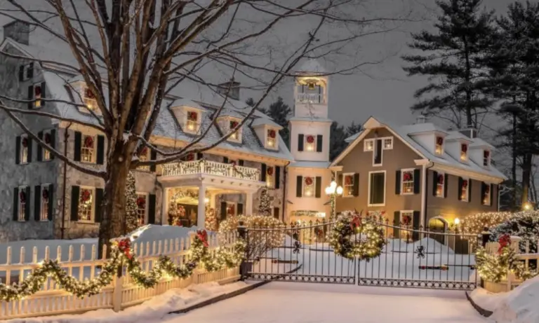 A grand home beautifully decorated with Christmas lights and garlands in a snowy setting.